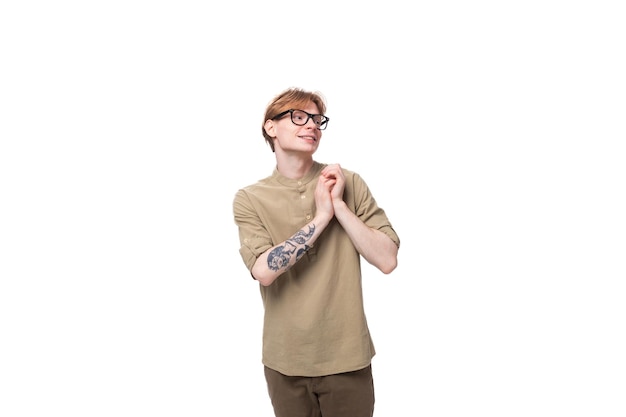 Smart young redhaired man in a beige shirt wears eyeglasses on a white background