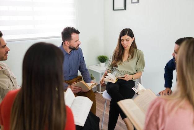 Smart young woman talking about a new novel on her book club. Group of people sitting in a circle and discussing a book