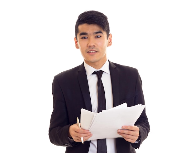 Smartlooking man with black hair in white shirt and black suit with black tie holding papers