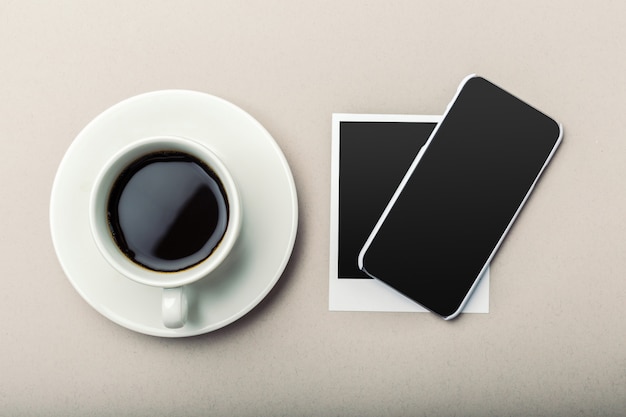 Smartphone beside of coffee on wooden table.