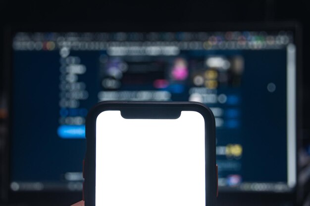写真 スマートフォンの空白画面と夜のコンピュータディスプレイ