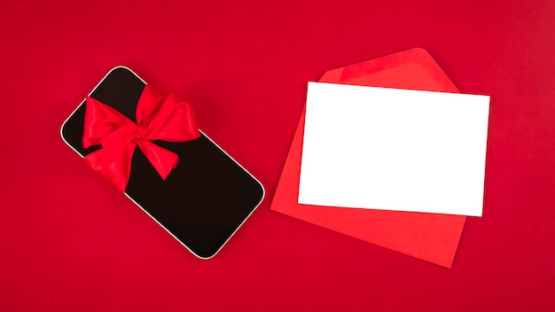 Smartphone and blank white paper note with red envelope against red background