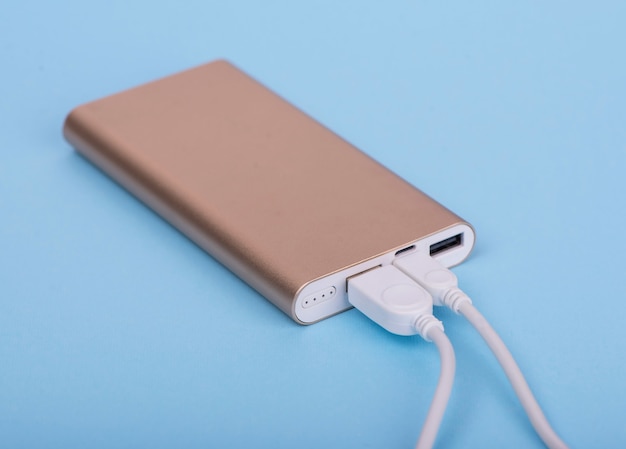 Smartphone in carica con power bank su sfondo blu.