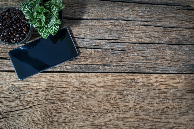 Photo smartphone and the coffee bean cup are placed on the wooden table top view