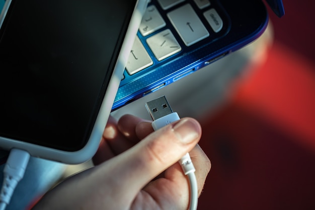 A smartphone connected to a laptop using a USB cable, phone charging, data exchange.