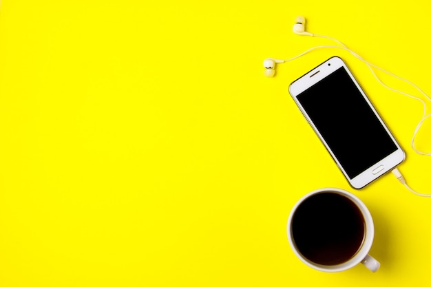 スマートフォンと黄色の背景に一杯のコーヒー