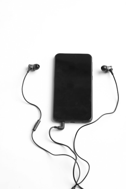 Smartphone and earphone or headphone on white surface