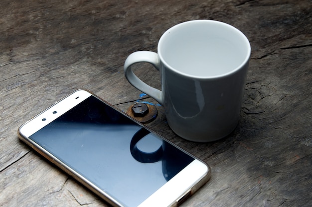 smartphone en lege kop koffie op houten.