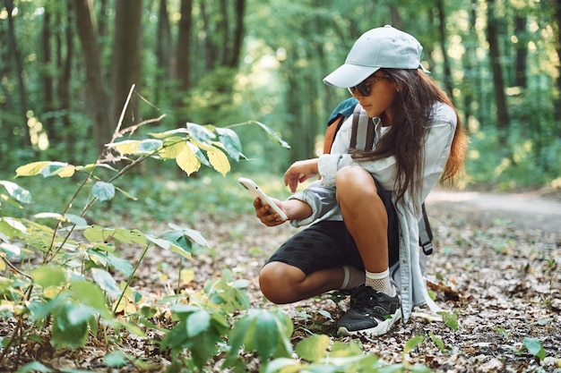 Smartphone gebruiken om foto's te maken Meisje is op zomerdag in het bos en ontdekt nieuwe plekken