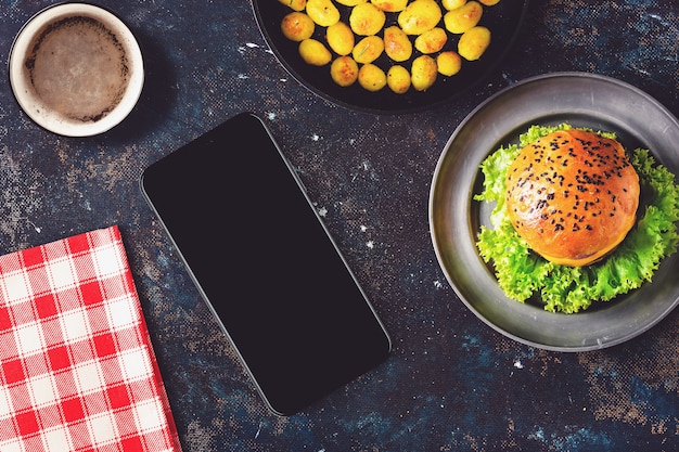 Photo smartphone and hamburger on a restaurant table