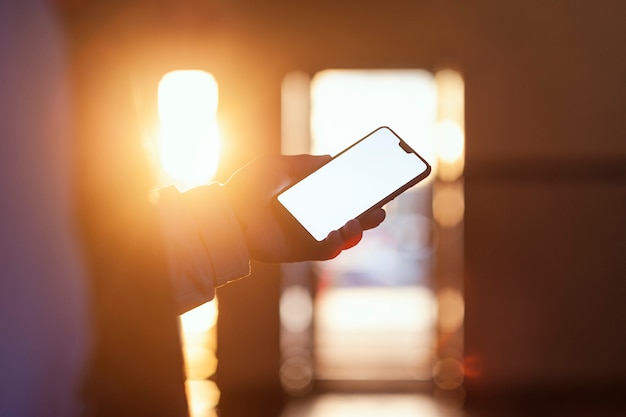 the smartphone in the hand of the guy against the sunset.