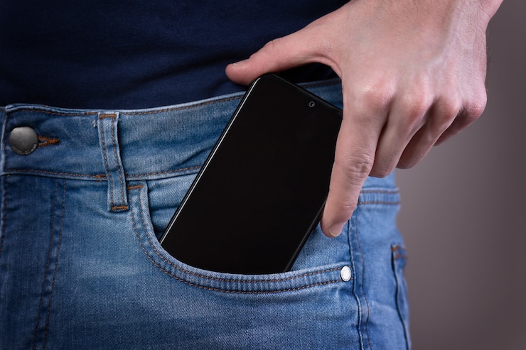 ジーンズのポケットにスマートフォンを手に