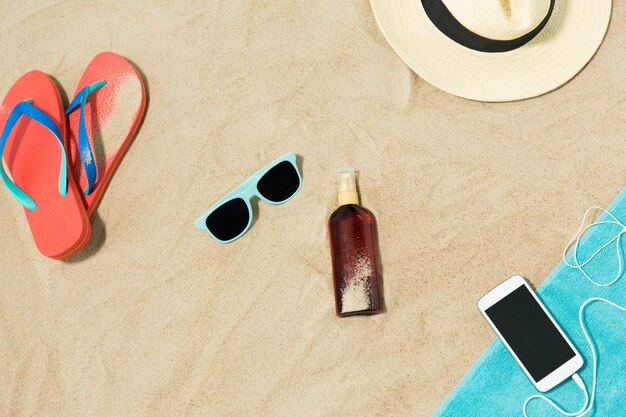 smartphone hat flip flops and shades on beach