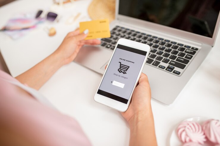 Photo smartphone held by young contemporary mobile shopper searching for goods to add new ones in basket