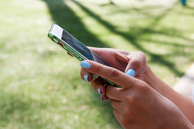 Foto smartphone in handen van de vrouw met blauwe manicure