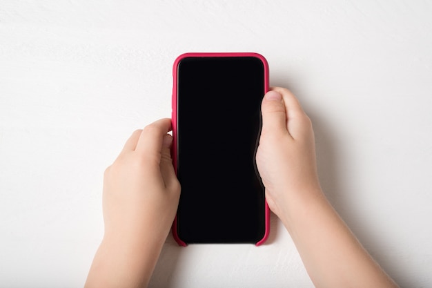 Smartphone in kinderhanden op een lichte ondergrond