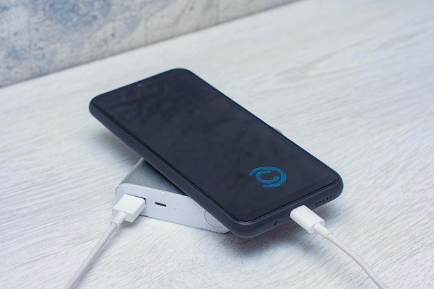 Photo the smartphone is being charged using a portable charger on a wooden table