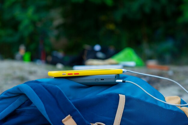 Smartphone is charged using a portable charger. Power Bank charges the phone outdoors with a backpack for tourism in nature.