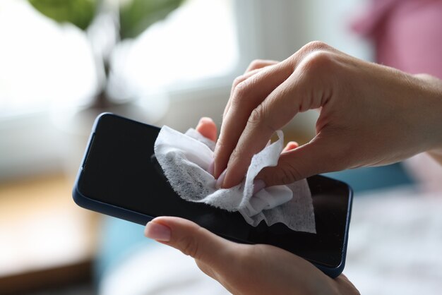 Smartphone is held in woman's hand and treated with antibacterial napkin