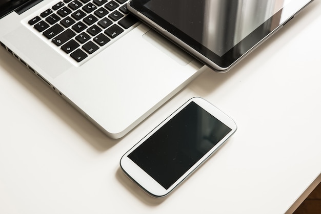 Photo a smartphone, a laptop computer and a tablet pc together on a desktop.