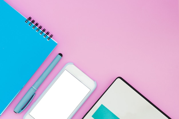 Smartphone, laptop and notebook on a pink background. Top view. Working space Flat La Layout