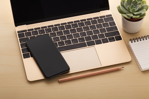 Smartphone on laptop on wooden table