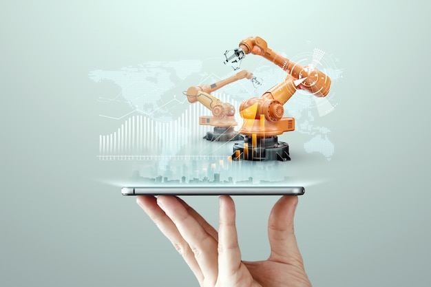 Smartphone in a man's hand and robotic arms of a modern plant. Iot technology concept, smart factory. Digital manufacturing operation. Industry 4.0.