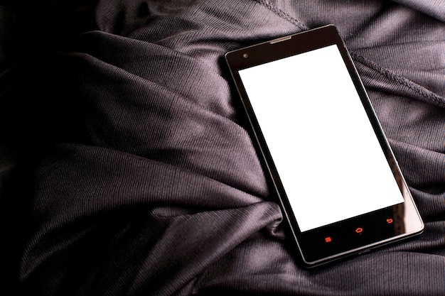 Smartphone met blanco wit display voor mockups op een gevouwen satijnen zwarte doek