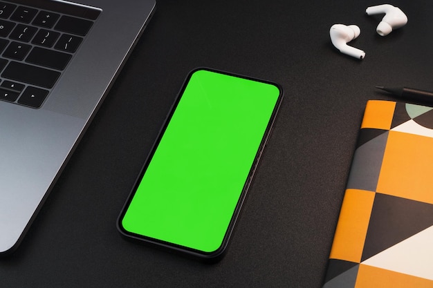 Smartphone met groen scherm op tafel met zwarte achtergrond Kantooromgeving Chroma Key