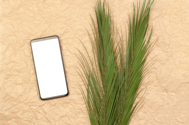 Smartphone met leeg wit display op verfrommelde beige achtergrond met palmbladeren