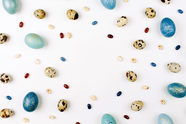 Smartphone Mock up with stylish Easter decorations. Painted  turquoise  Easter eggs and quail eggs on a white background with copy space. Holiday background. Flat lay, top view