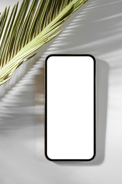 Photo smartphone mockup with palm leaf on white background device screen mock up on stylish background for presentation or appl design