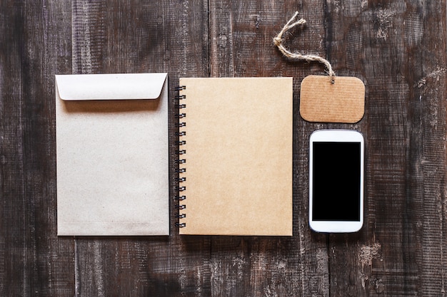 Smartphone on notebook and calico bags on old wooden table