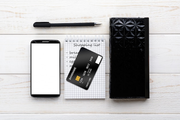 Smartphone, notebook, pen and credit card on a white table