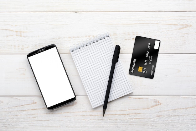 Smartphone, notebook, pen and credit card on a white table