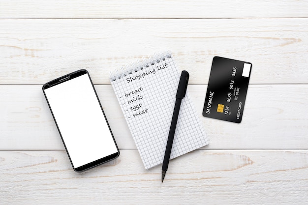 Smartphone, notebook, pen and credit card on a white table