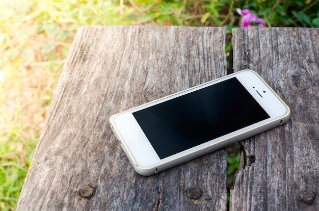 Smartphone on old brown wood background in the garden