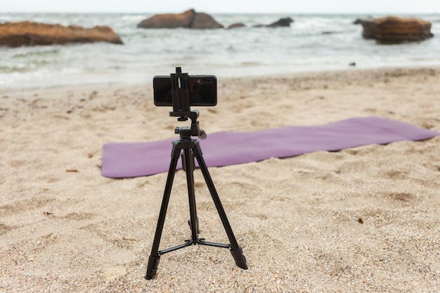 Smartphone op statief op het strand Fitness blog concept