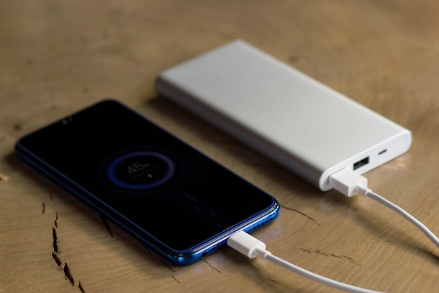 Smartphone opladen met powerbank op houten tafel. Opladen aandeel concept.