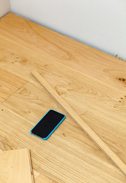 Smartphone on the parquet during its installation Telephone contact concept for parquet flooring professional with copy space