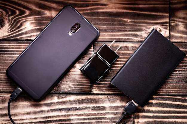 smartphone and power bank cable charge on wood background texture.