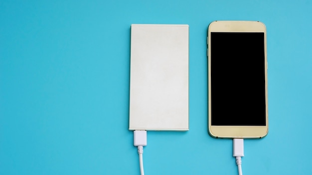 Smartphone and power bank for charging mobile devices on a blue background.