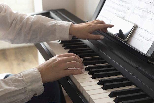 Smartphone screen in female hands near the piano.