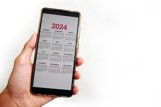 Foto smartphone sullo schermo con calendario per il 2024 in mani maschili telefono android con calendario per el 2024 su s