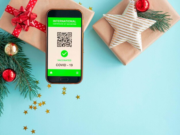 Smartphone shows certificate of vaccination against covid19\
coronavirus on christmas background