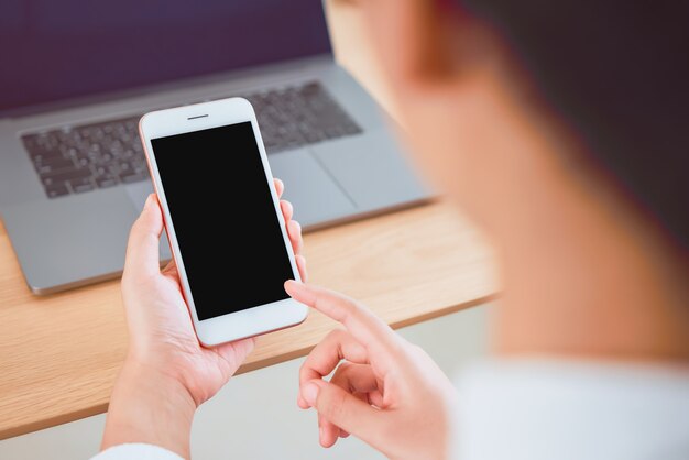 Smartphone van de handholding met het lege scherm op lijst in koffie