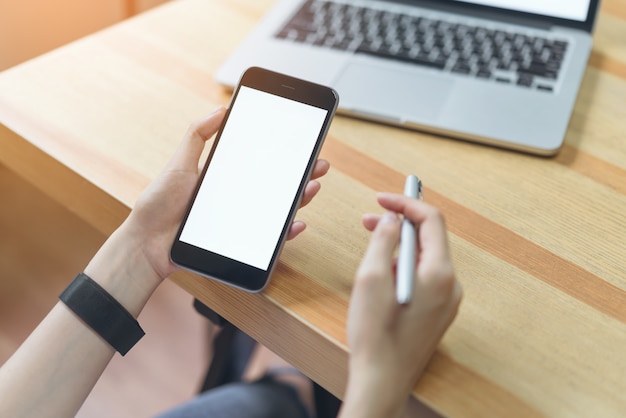 smartphone van de vrouwenholding en het gebruiken van laptop op lijst in bureauruimte.