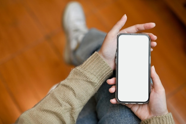 A smartphone white screen mockup is in a woman's hands over blurred background