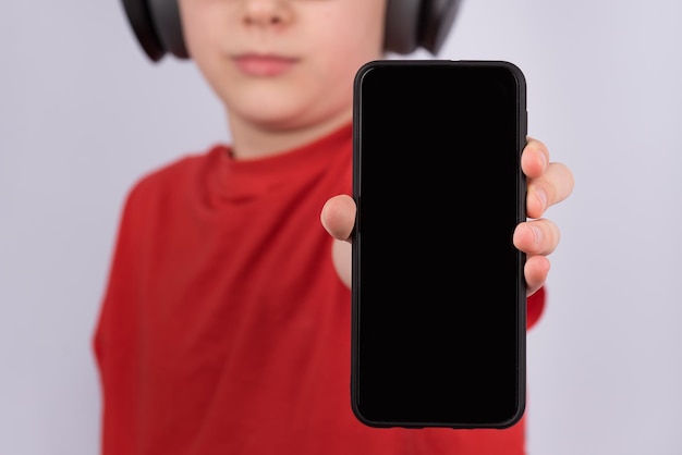 Smartphone with black blank display in childs hand Mobile phone close up Copy space Mockup