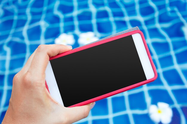 Smartphone with black screen near pool. Vacation concept